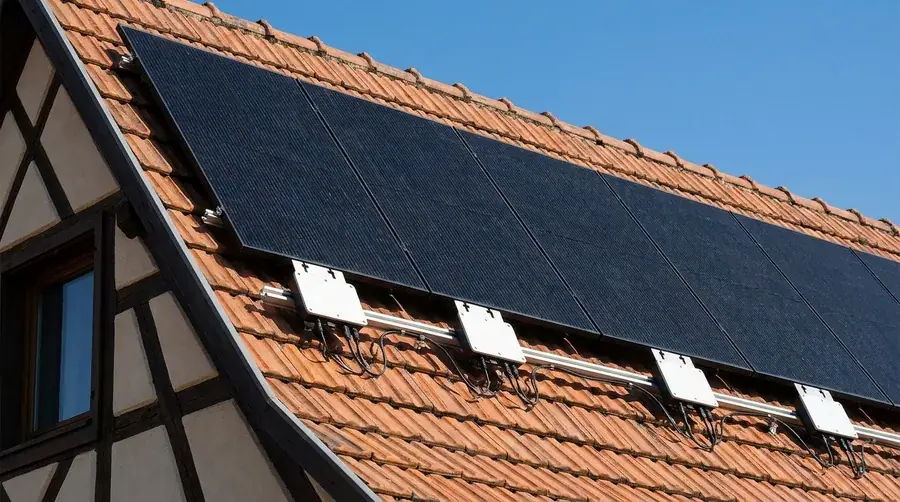 Micro-onduleurs blancs installés sous des panneaux solaires en toiture